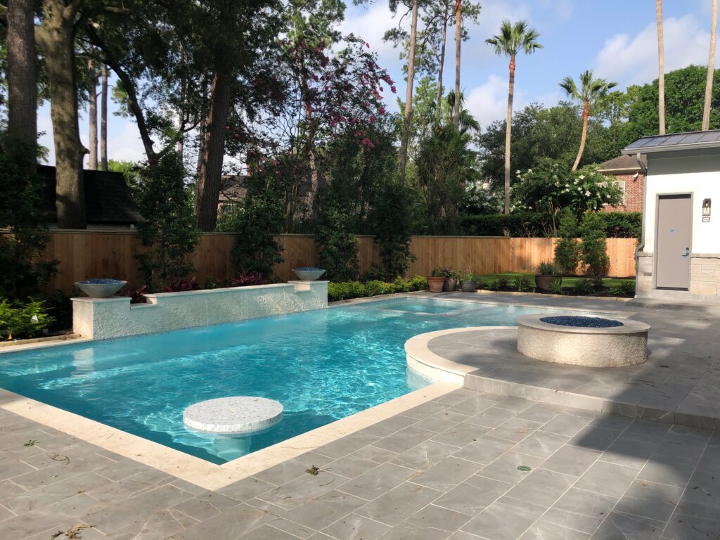 custom-pool-swim-up-dining-table-memorial-villages-houston Custom luxury pool in Memorial Villages, Houston, featuring a swim-up dining table, raised beam water feature, and premium plaster finish.