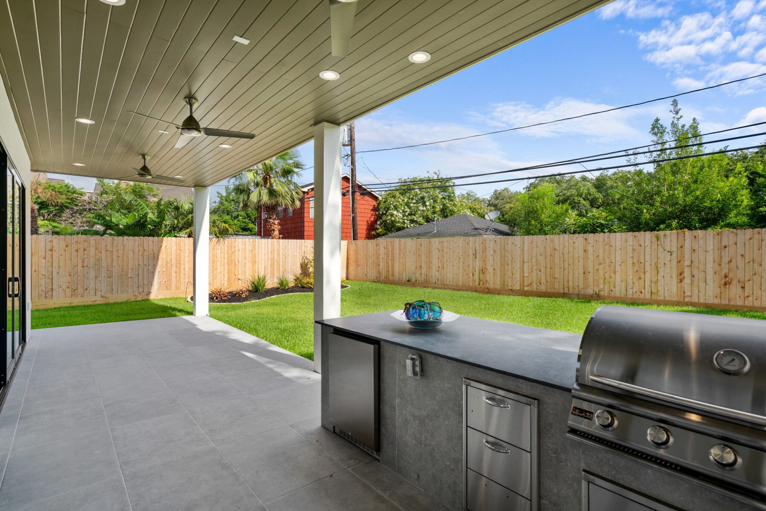 A 7-foot tall cedar privacy fence installed around a property perimeter, featuring an outdoor kitchen and dining area nestled under a covered patio.