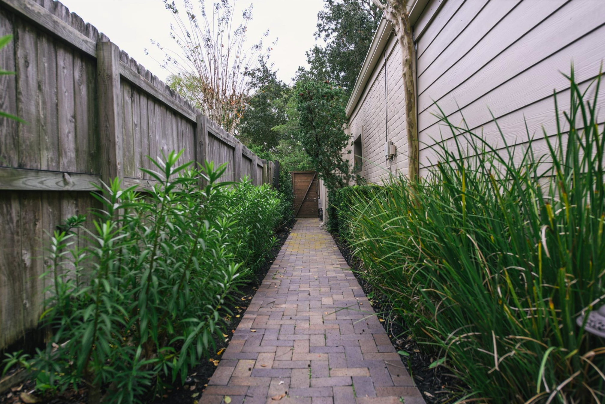 Durable side house walkway featuring interlocking pavers in a 45-degree herringbone pattern to prevent shifting.