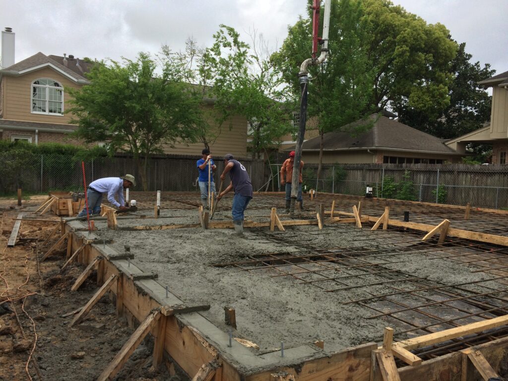 uxscape-west-university-concrete-foundation-pour-boom-pump Custom concrete construction in Houston showing a foundation pour using a concrete boom pump over steel rebar in West University.