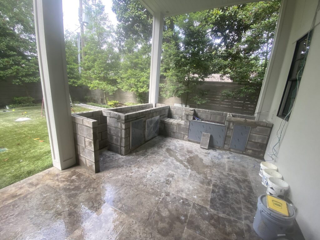 Tanglewood Outdoor Kitchen CMU Core Construction A custom project by a premier outdoor kitchen builder in Houston, showing a gray cinder block core structure with installed stainless steel access doors before the stone facade is applied.