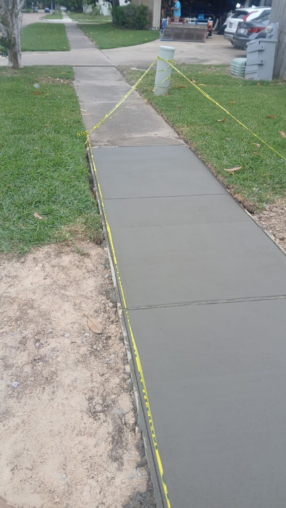Concrete Newly poured wet concrete sidewalk with strategic expansion joints spaced every six feet to reduce future cracking.