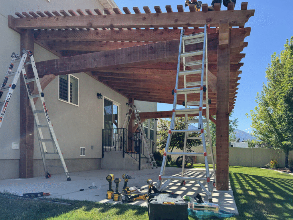 Precision Handcrafted Workmanship by Houston Pergola Builders A premium Red Cedar pergola under construction in a spacious backyard, showcasing heavy-duty timber posts and custom rafter installation by professional Houston pergola builders.