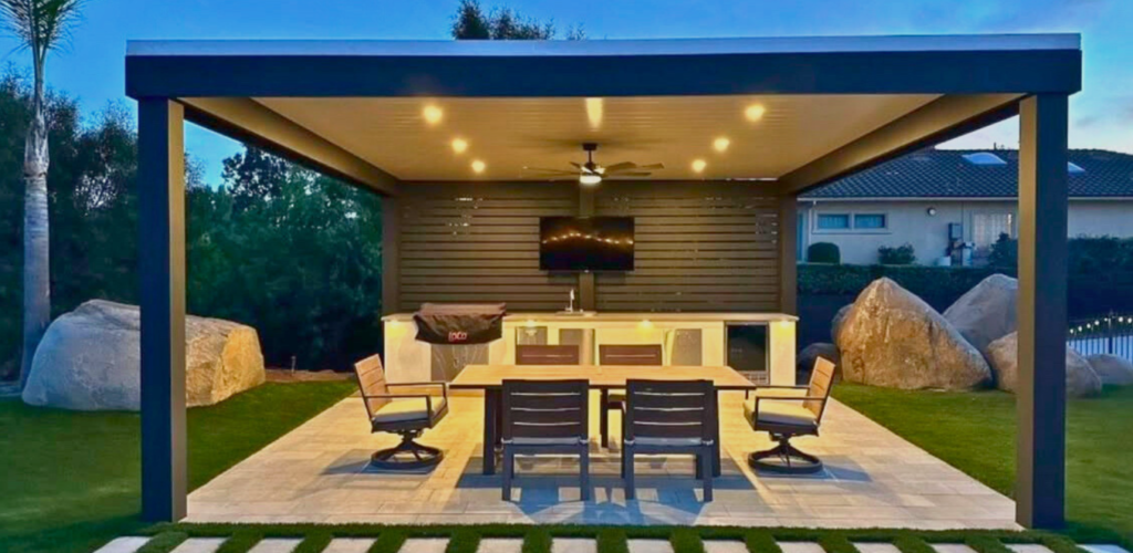 Modern 4K aluminum patio cover in Katy featuring an integrated privacy slat wall, tile flooring, and a linear outdoor kitchen with a sink and wall-mounted TV.