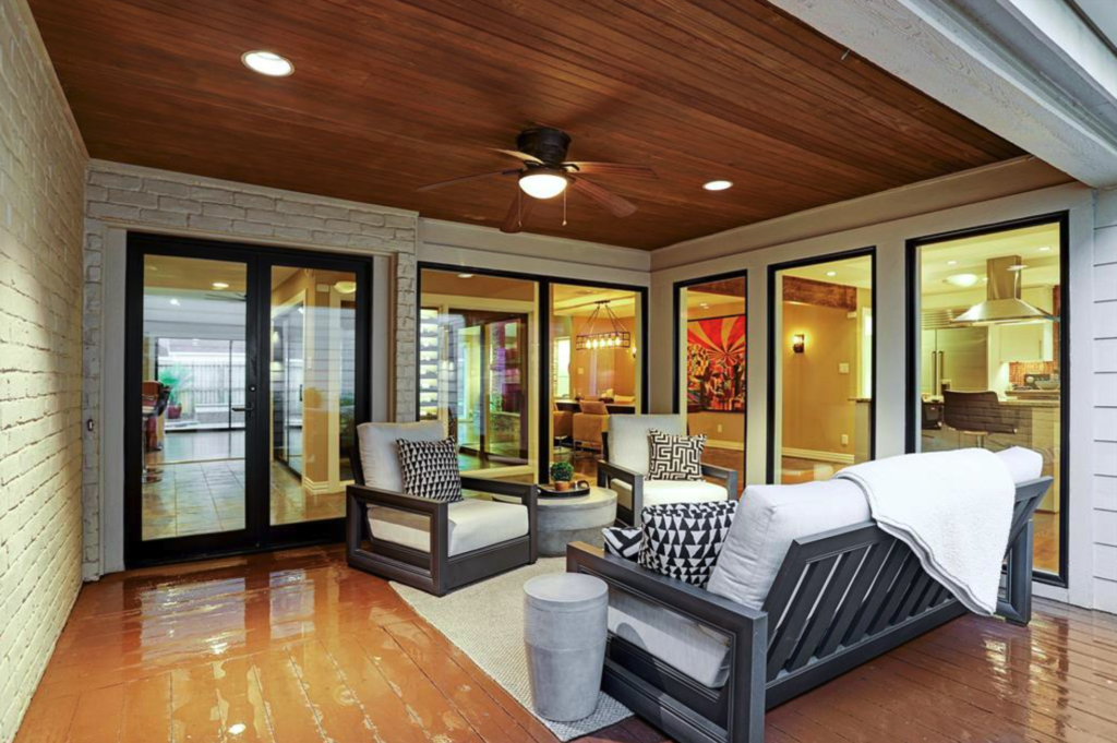 Custom patio cover built over a wood deck in Katy featuring a stained cedar tongue and groove ceiling, a ceiling fan, and recessed LED can lights.
