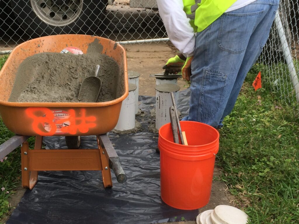 Technician sampling fresh concrete for quality control testing during a pour, designed for Cypress homeowners by Luxscape Outdoor Builders serving Houston, TX.
