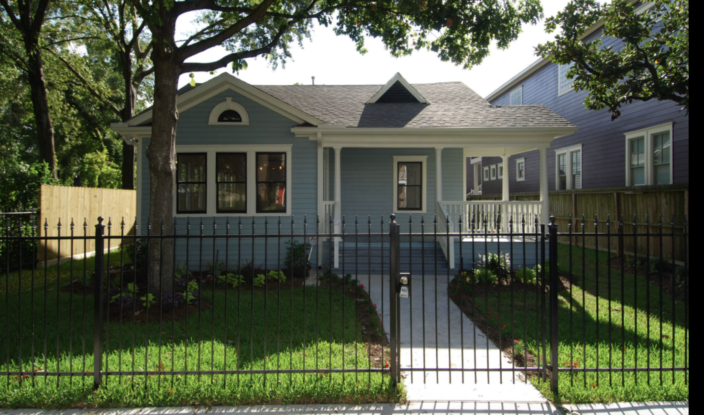A remodeled Historic Heights bungalow with blue siding, a covered porch and a black wrought iron fence, Luxscape Outdoor Builders serving Houston, TX.