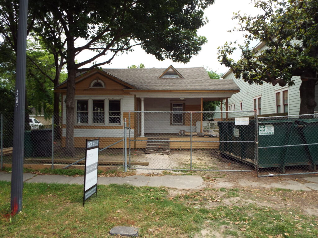 A Historic Heights bungalow before its remodel, with construction fencing in the front yard, Luxscape Outdoor Builders serving Houston, TX.
